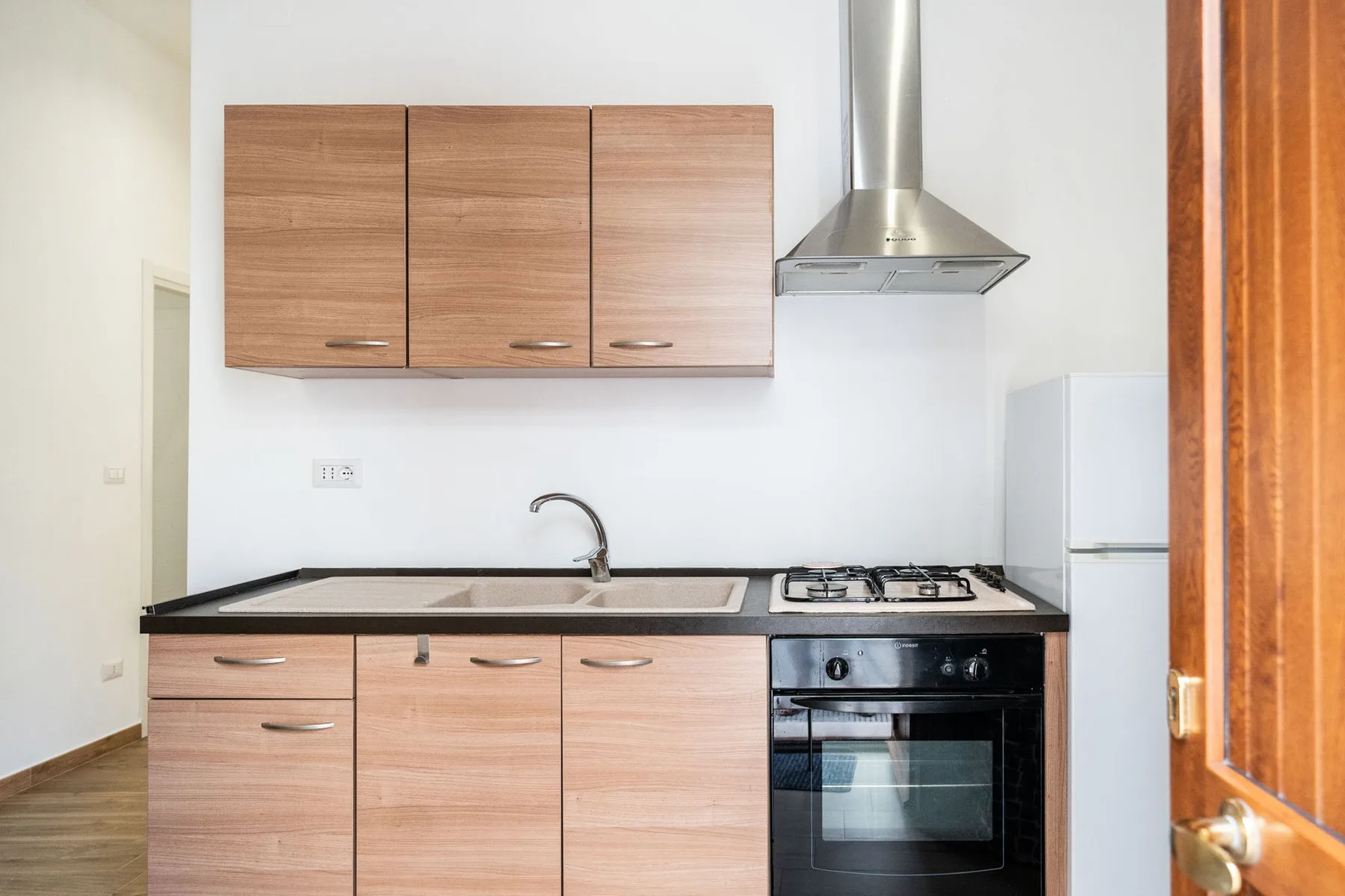 A compact kitchen with wooden cabinets, a sink, and a stove.