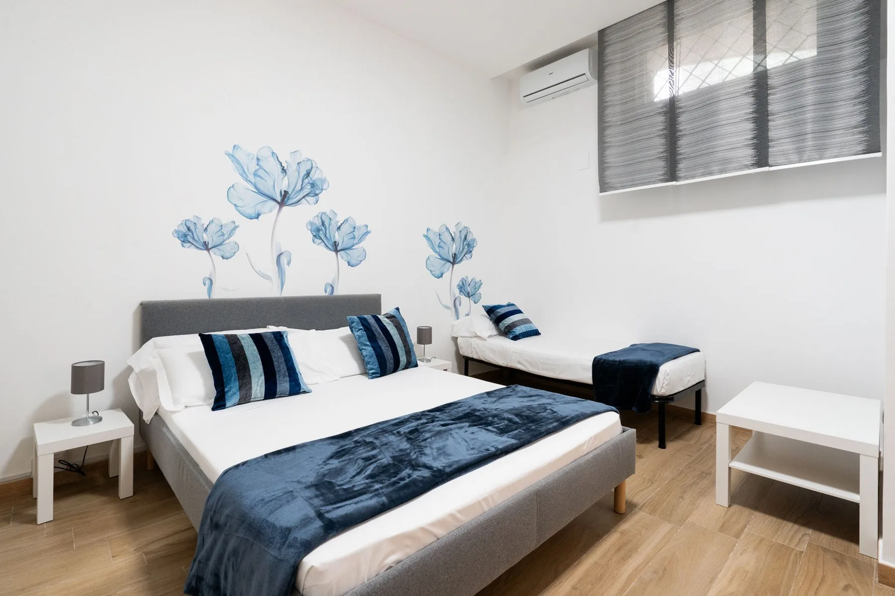 A bedroom with two beds dressed in blue and white linens.