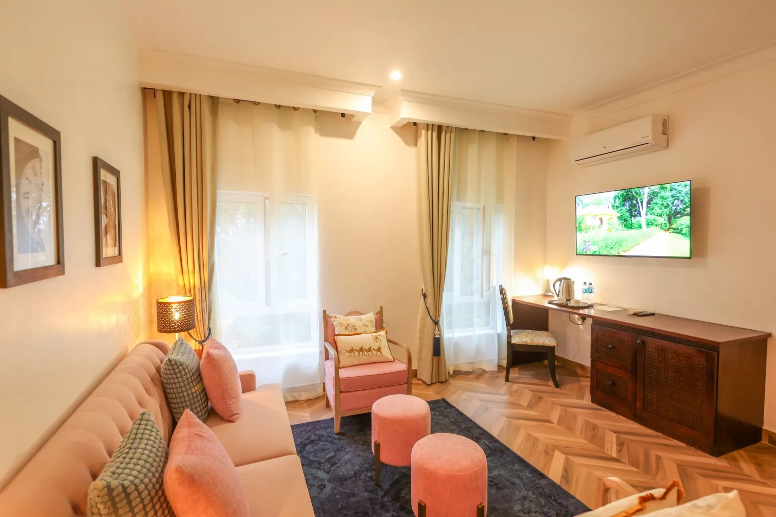 Una habitación Deluxe con sofá y pufs, escritorio, televisor montado en la pared y una ventana que da al jardín.