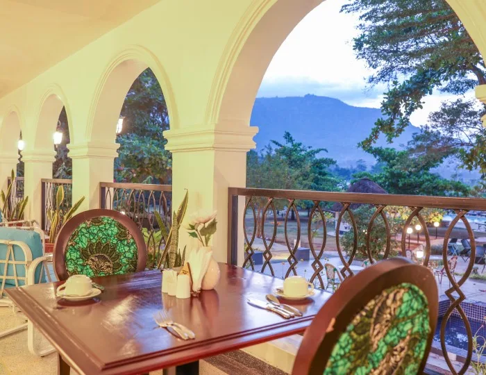Una mesa puesta en la veranda con arcos del restaurante Masaaba, con las colinas visibles a través del arco.