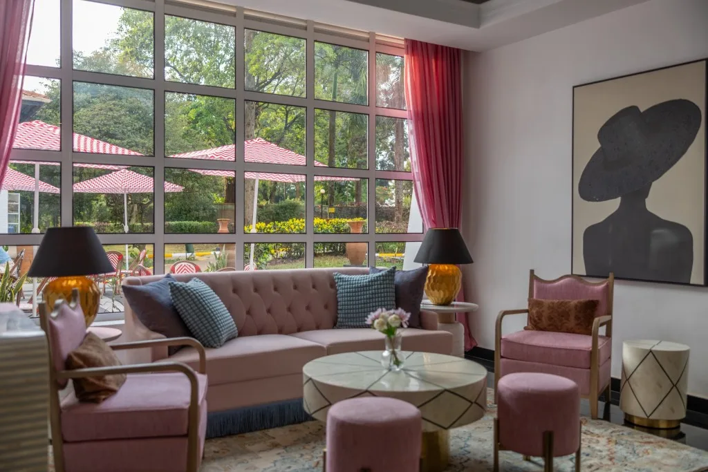 Un largo sofá capitoné y sillones en la zona de estar del vestíbulo, situados bajo ventanas altas con vistas al jardín.