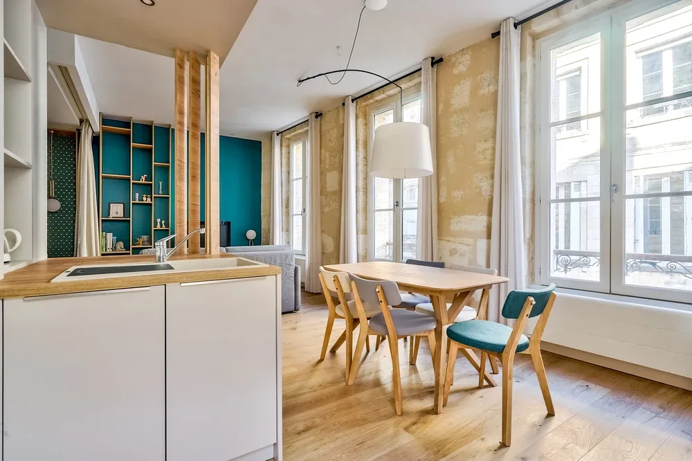 A bright open-plan kitchen and dining area with wooden seating and large windows.