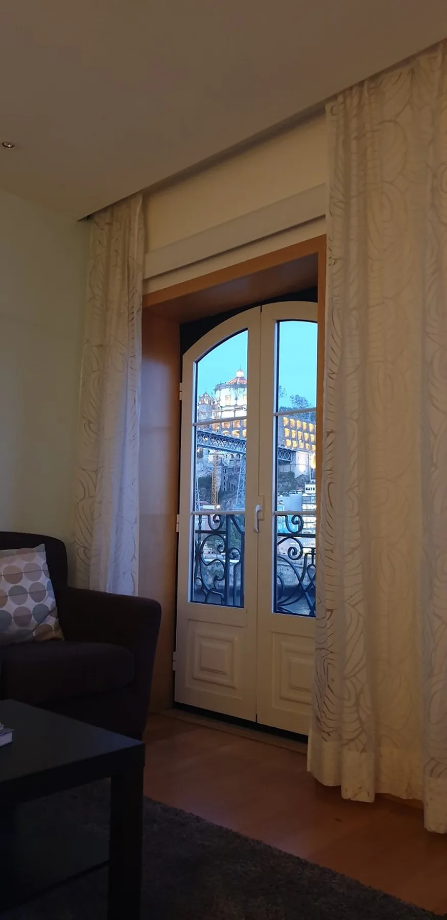 A living room with a curtained glass door opening onto a balcony.