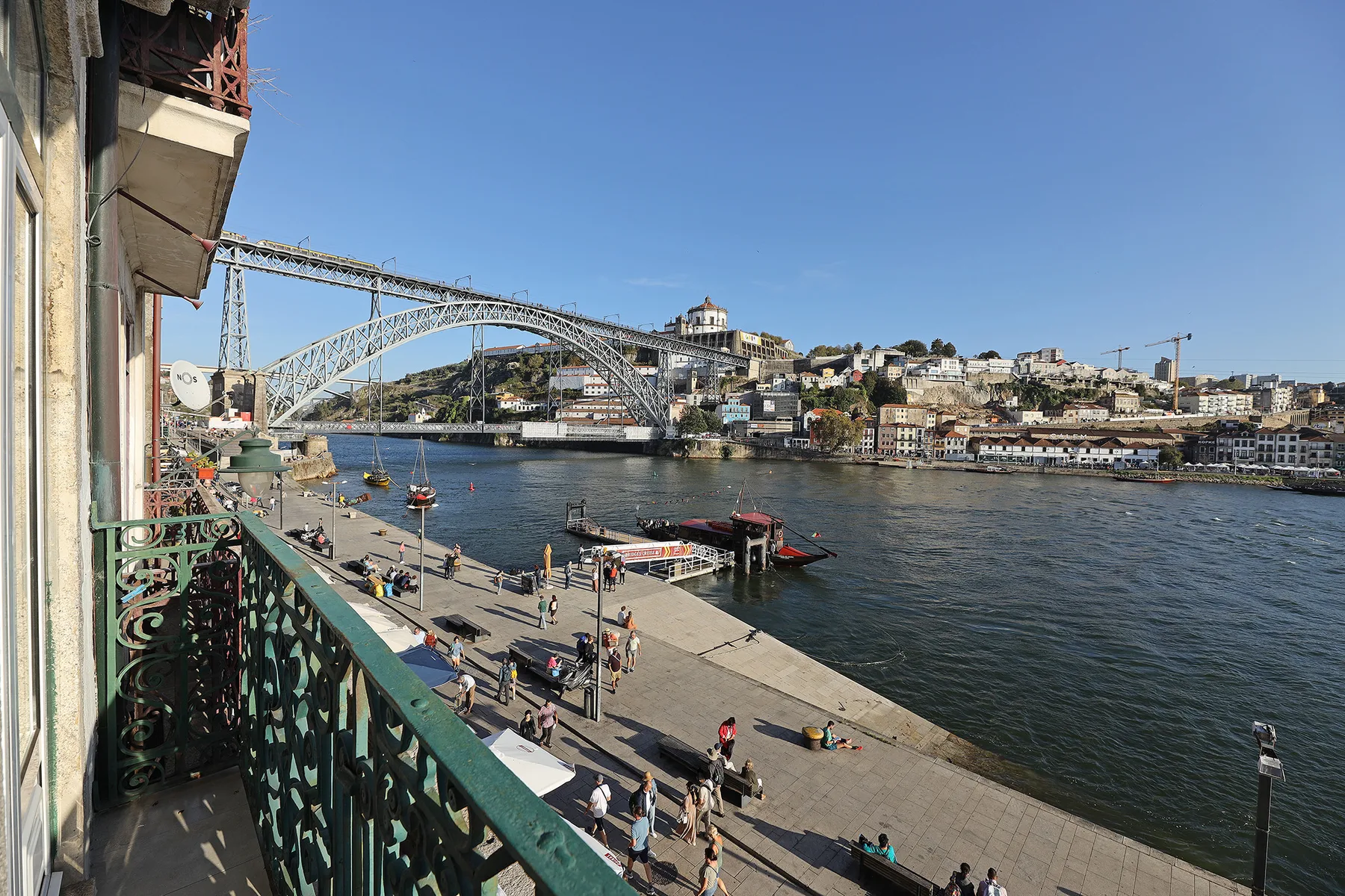A riverside promenade and bridge span the waterfront beneath a clear sky.