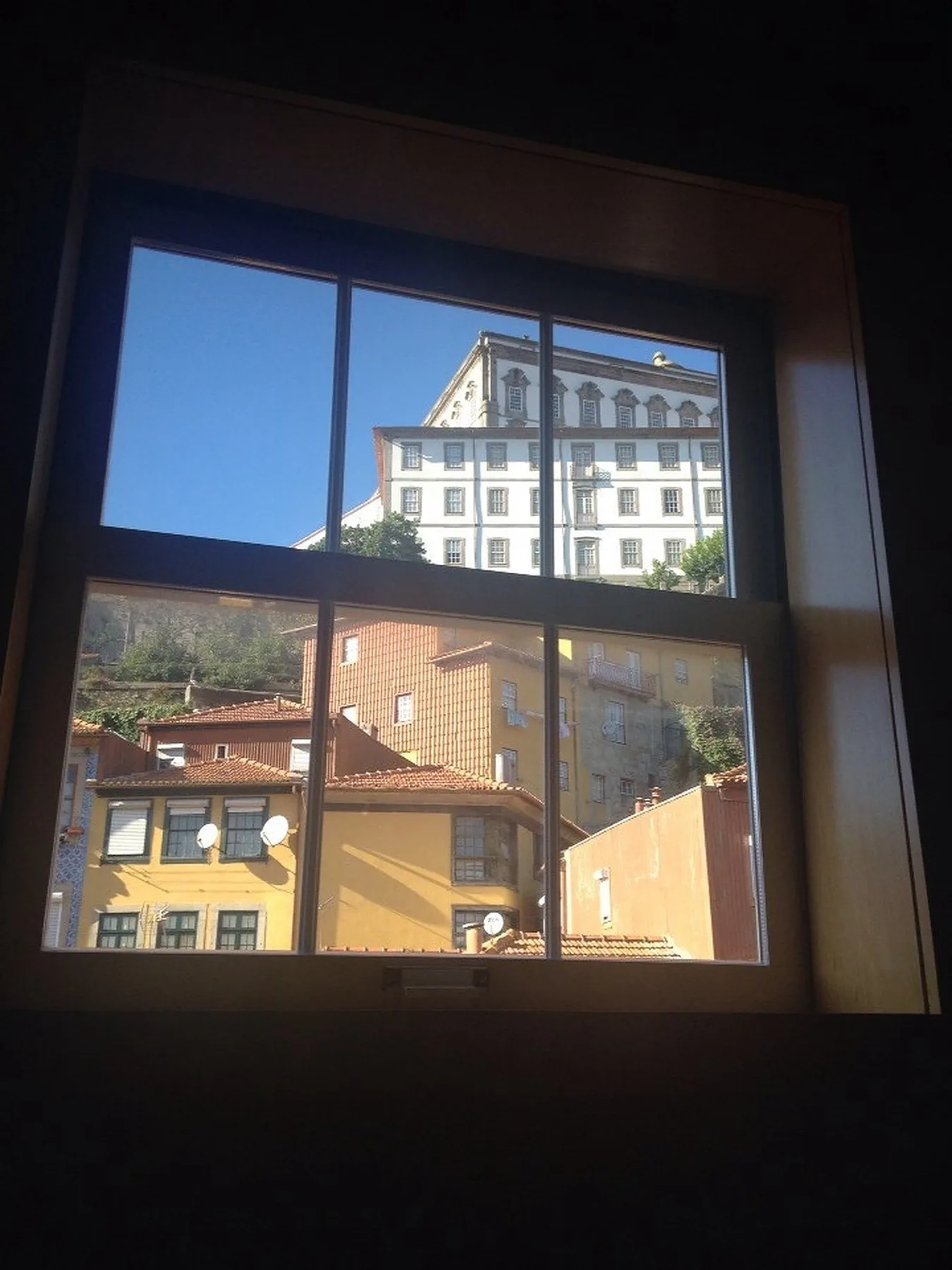 A window overlooks nearby city buildings beneath a clear blue sky.