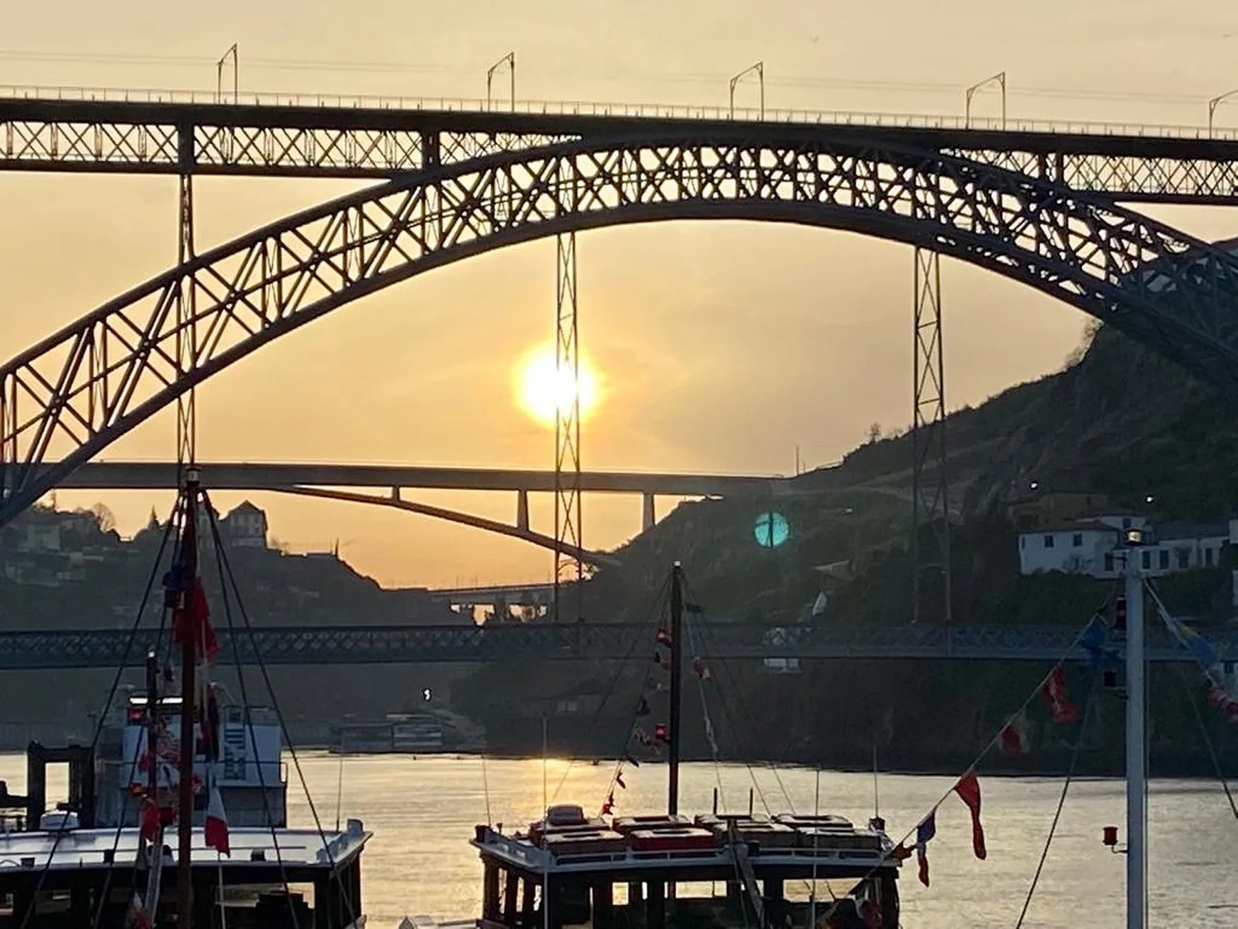 A river scene at sunset, with a large steel bridge spanning the water.