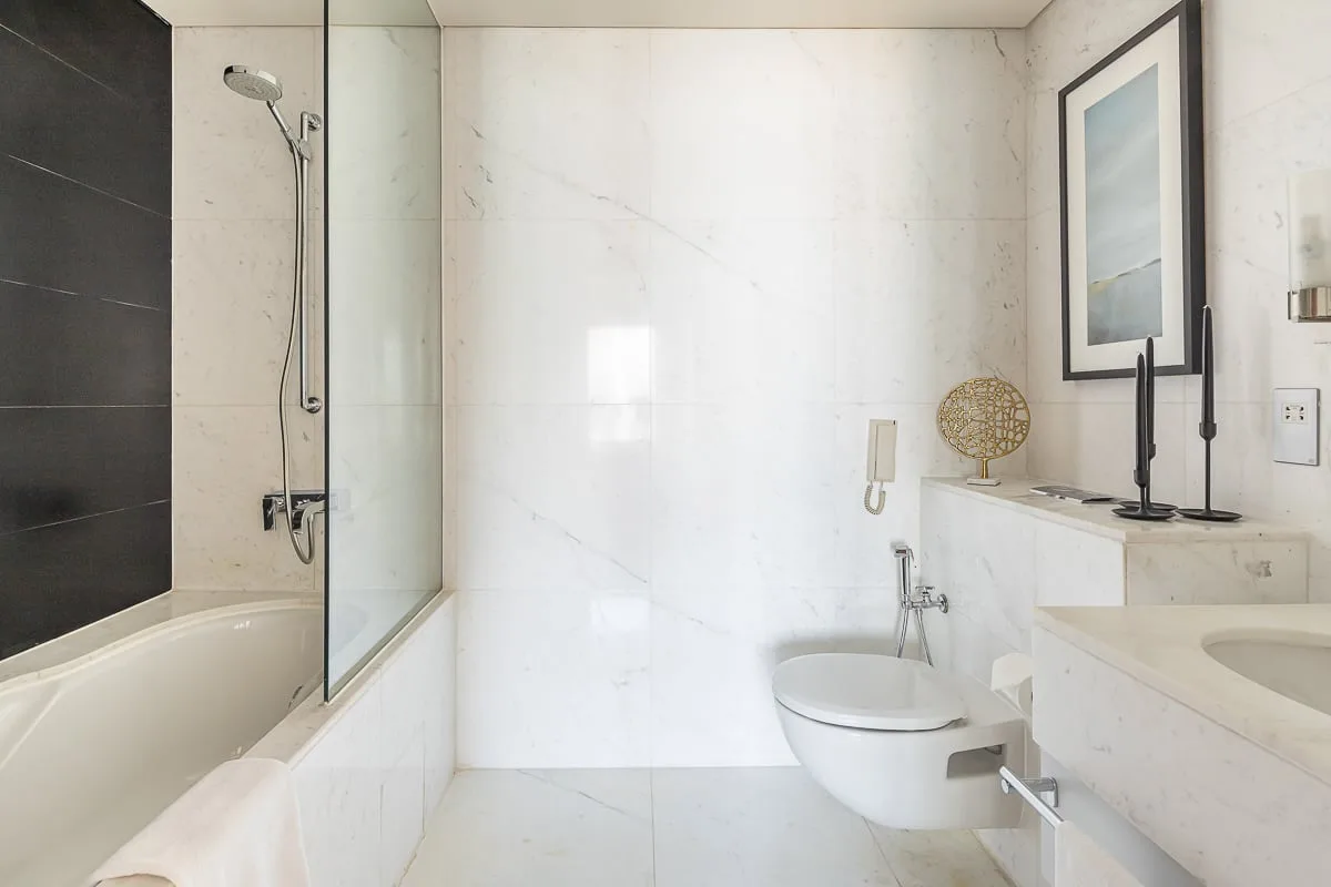 Un baño luminoso con bañera, ducha e inodoro suspendido.