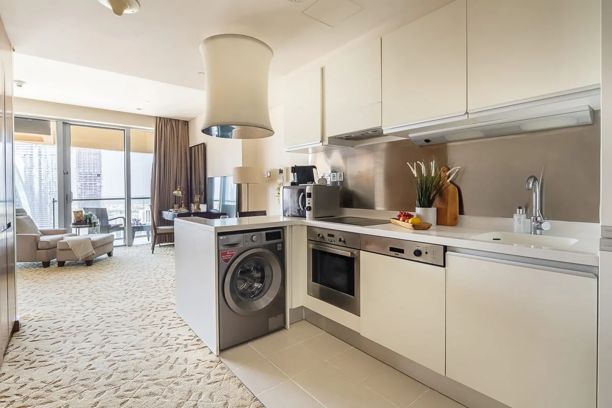 Una cocina abierta y luminosa con lavadora y zona de estar junto a las ventanas.