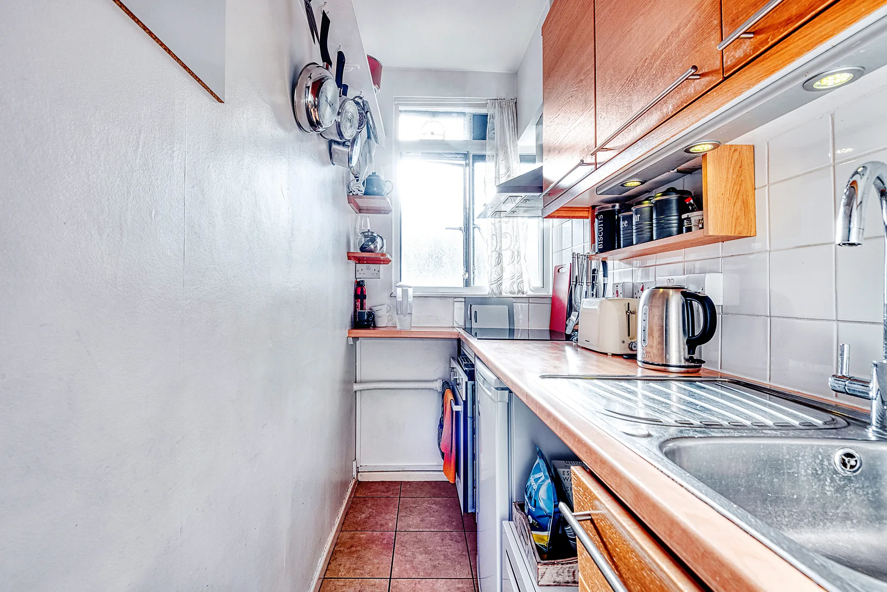 Una cocina estrecha con gabinetes de madera, una encimera y un fregadero.