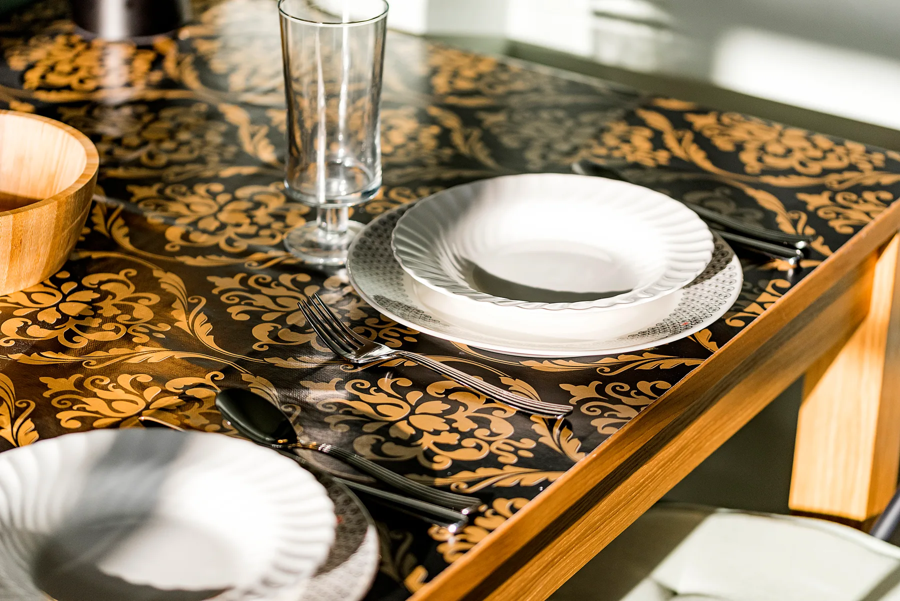 Una mesa de comedor está puesta con platos, cubiertos y un vaso.