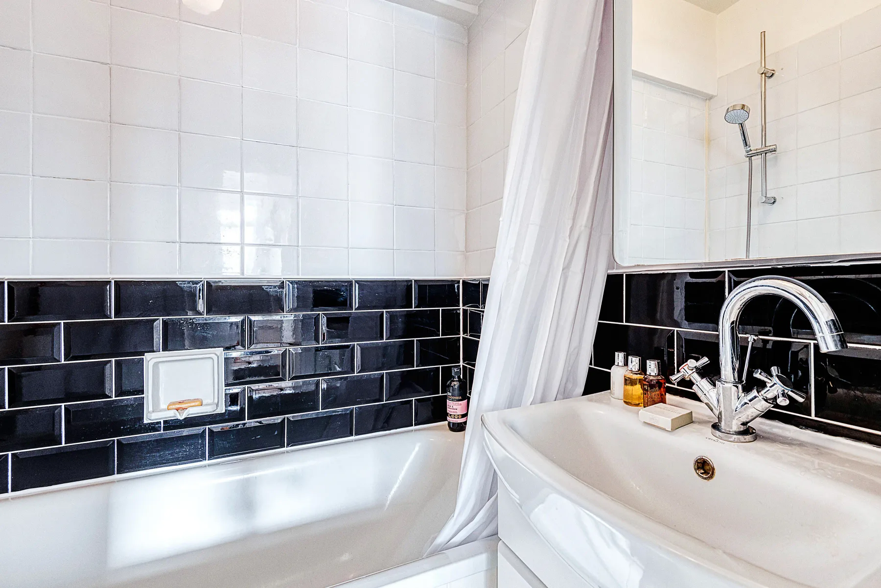 Un baño con azulejos, bañera, cortina de ducha y lavabo.