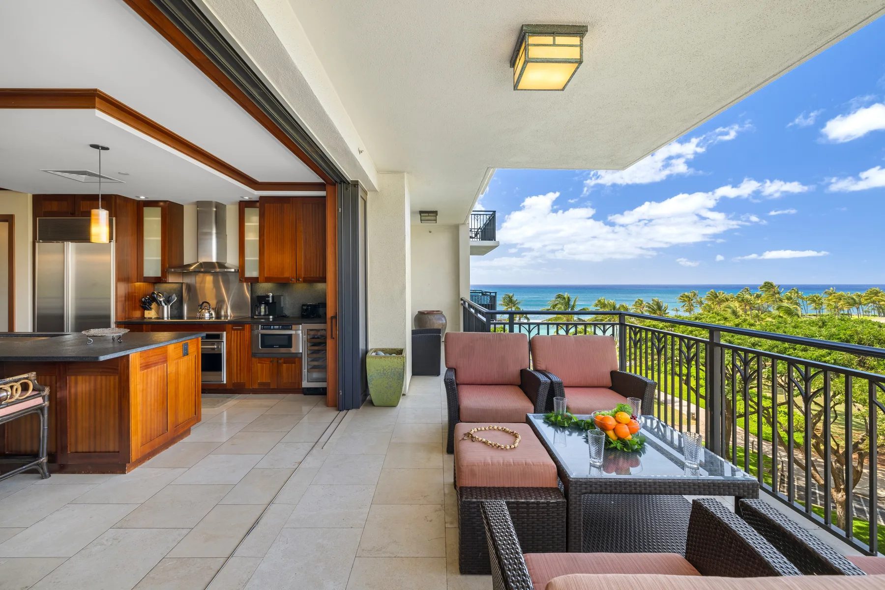 Una cocina abierta da a un patio cubierto con asientos y vistas al mar.