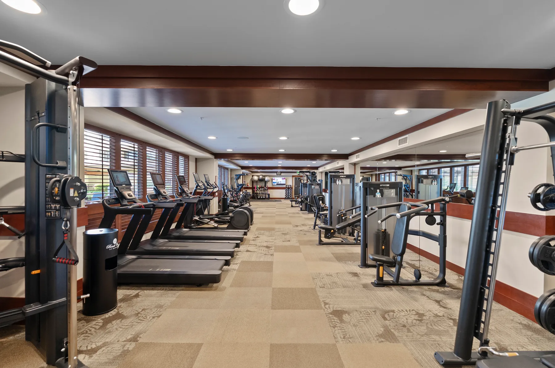 Una sala de ejercicio con filas de cintas de correr y máquinas de entrenamiento.