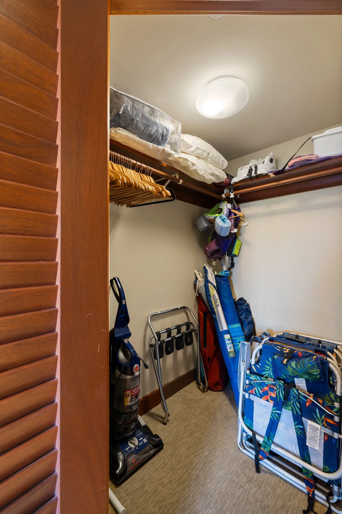 Un armario de almacenamiento con equipaje y ropa de cama doblada en estantes superiores.