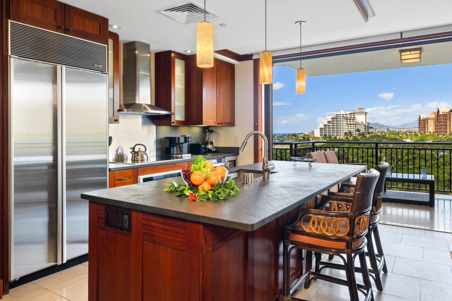 Una cocina moderna con una isla amplia se abre a un balcón con vistas a la ciudad.