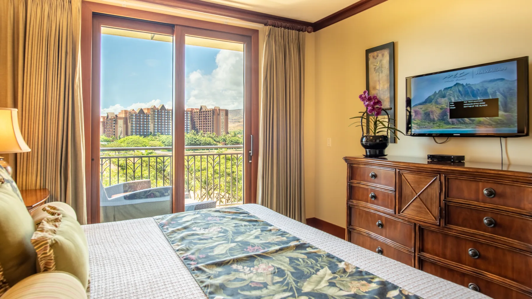 Un dormitorio con cama, cómoda y puertas corredizas de vidrio que dan a un balcón.