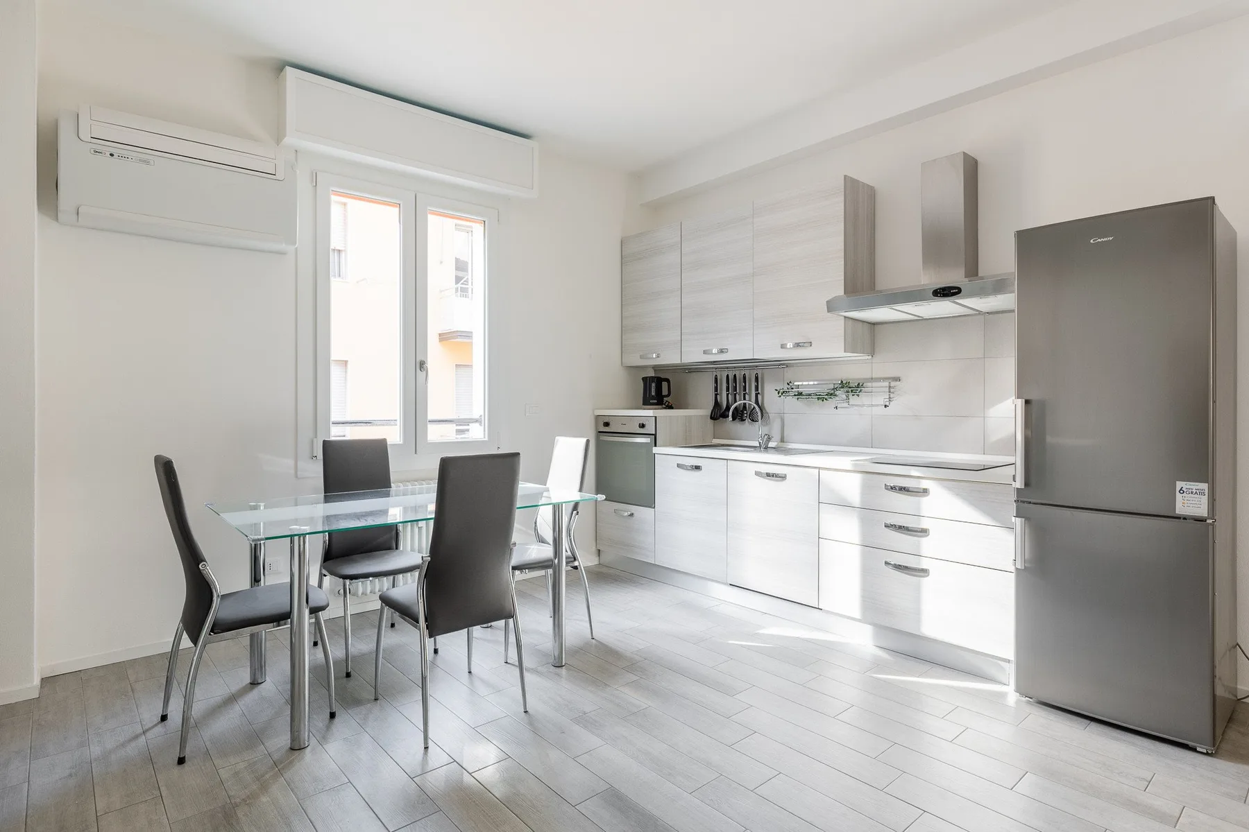 A bright kitchen and dining area with white cabinets and a glass dining table.