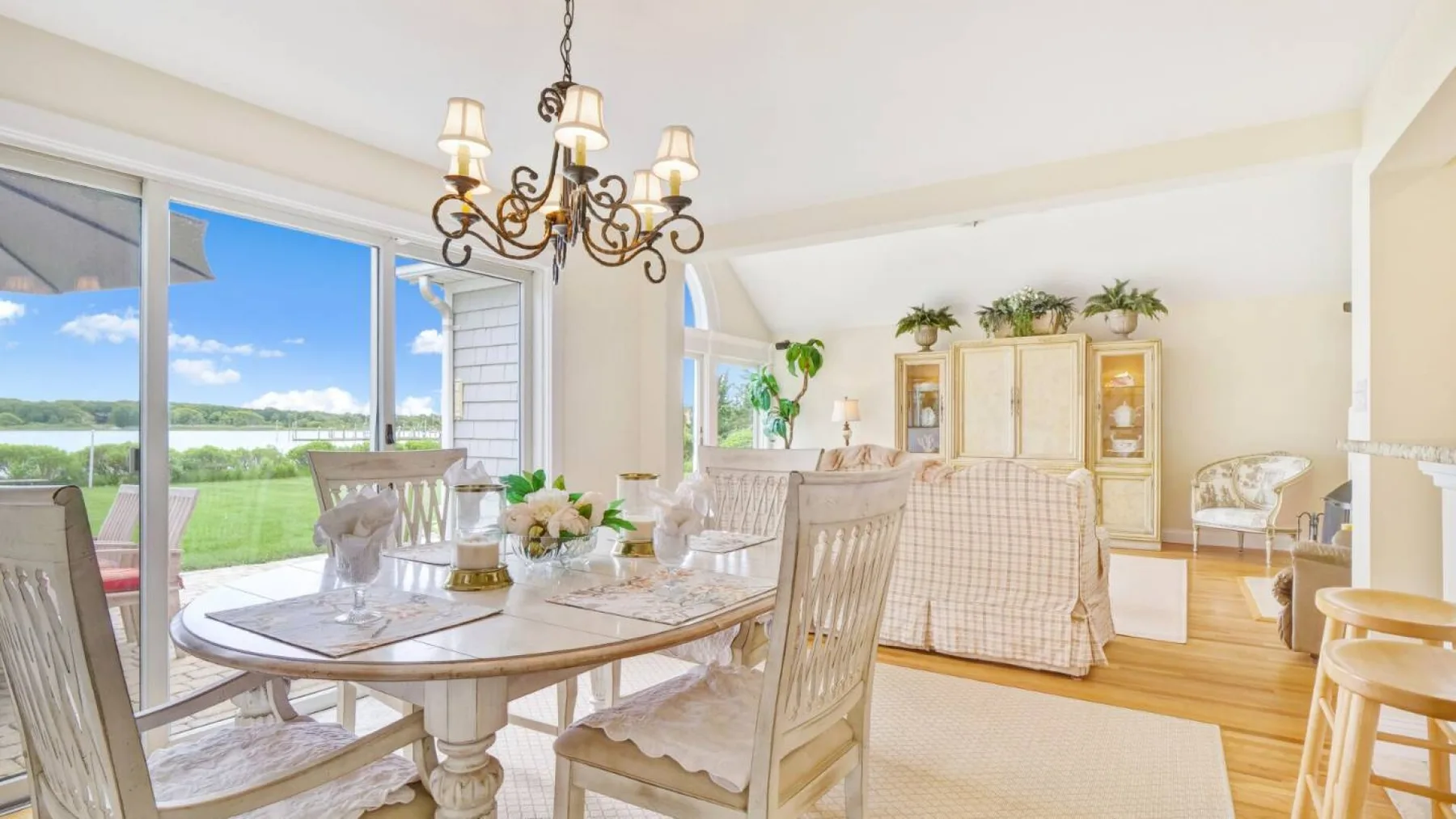 Un comedor luminoso se abre a un patio, con una mesa y sillas junto a una sala de estar.