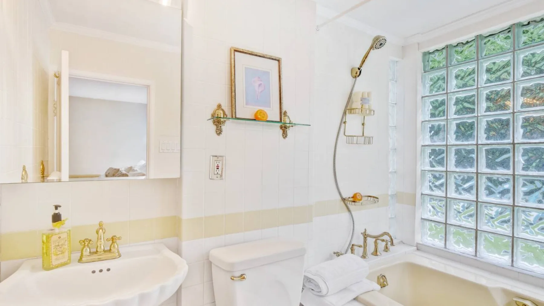 Un baño luminoso con bañera, inodoro y ventana de bloques de vidrio.