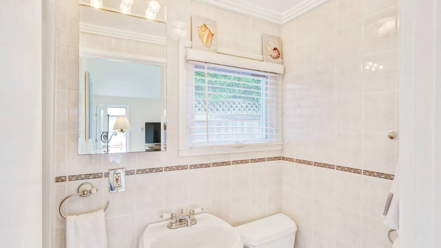 Un baño luminoso con azulejos, lavabo, inodoro y ventana.