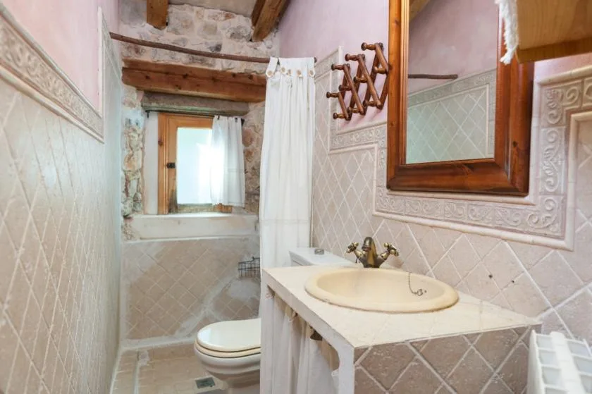 Un baño alicatado con lavabo, inodoro y una zona de ducha con cortina.