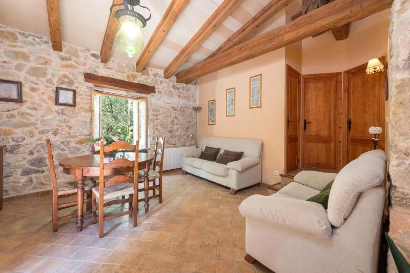 Una sala de estar y comedor rústica con paredes de piedra, vigas de madera y asientos.