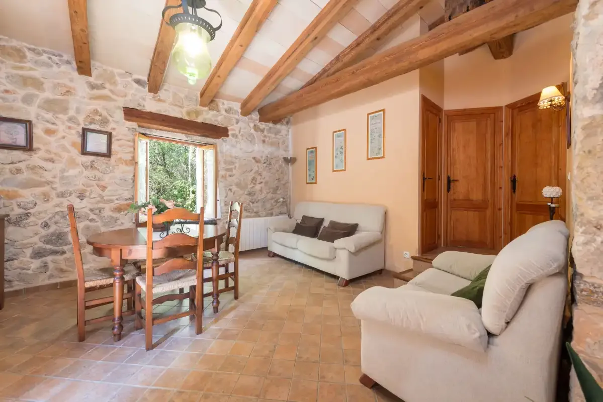 Un salón rústico con mesa de comedor, asientos y vigas de madera a la vista.