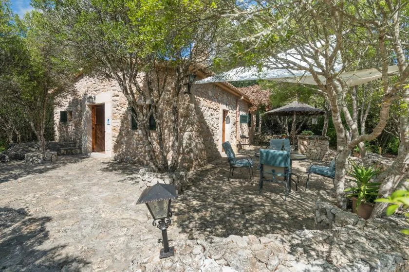 Un patio de piedra con asientos al aire libre bajo árboles frondosos.