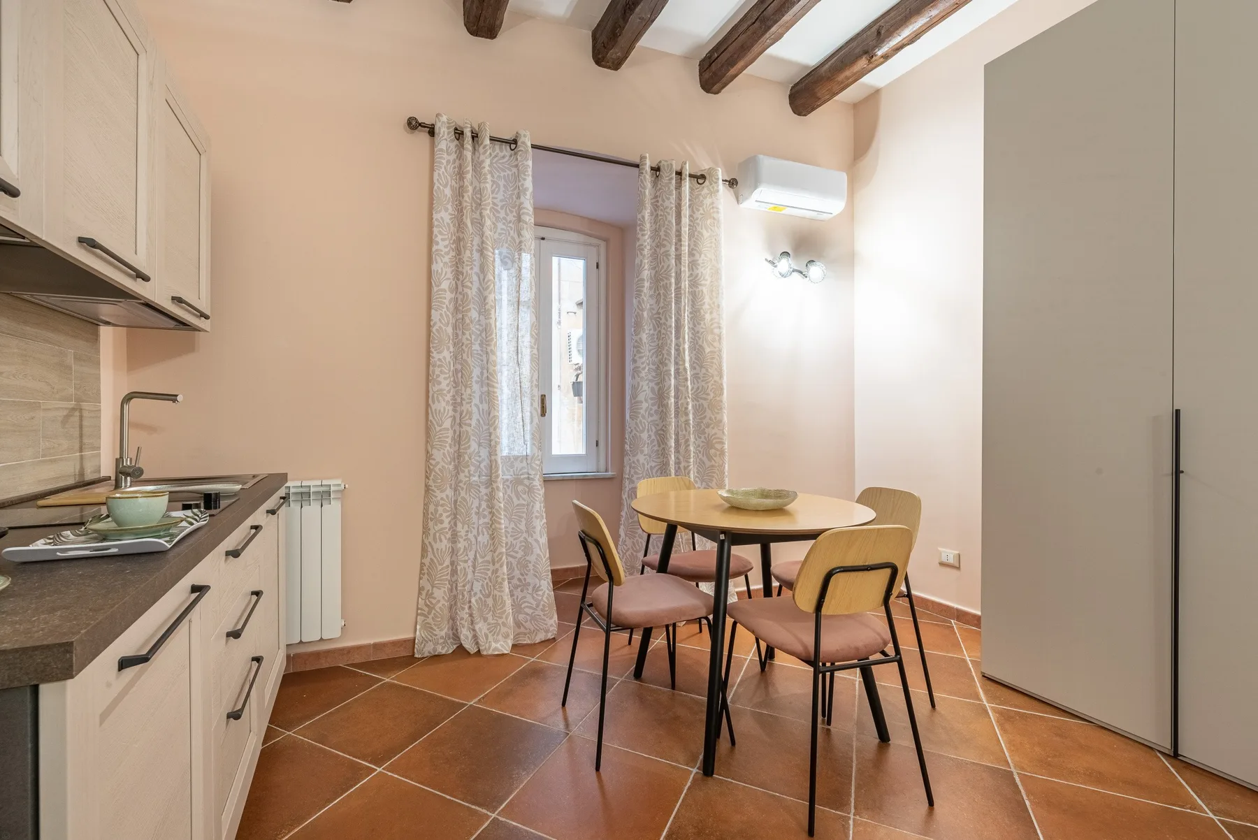 Comedor con una mesa redonda y sillas junto a una ventana con cortinas.