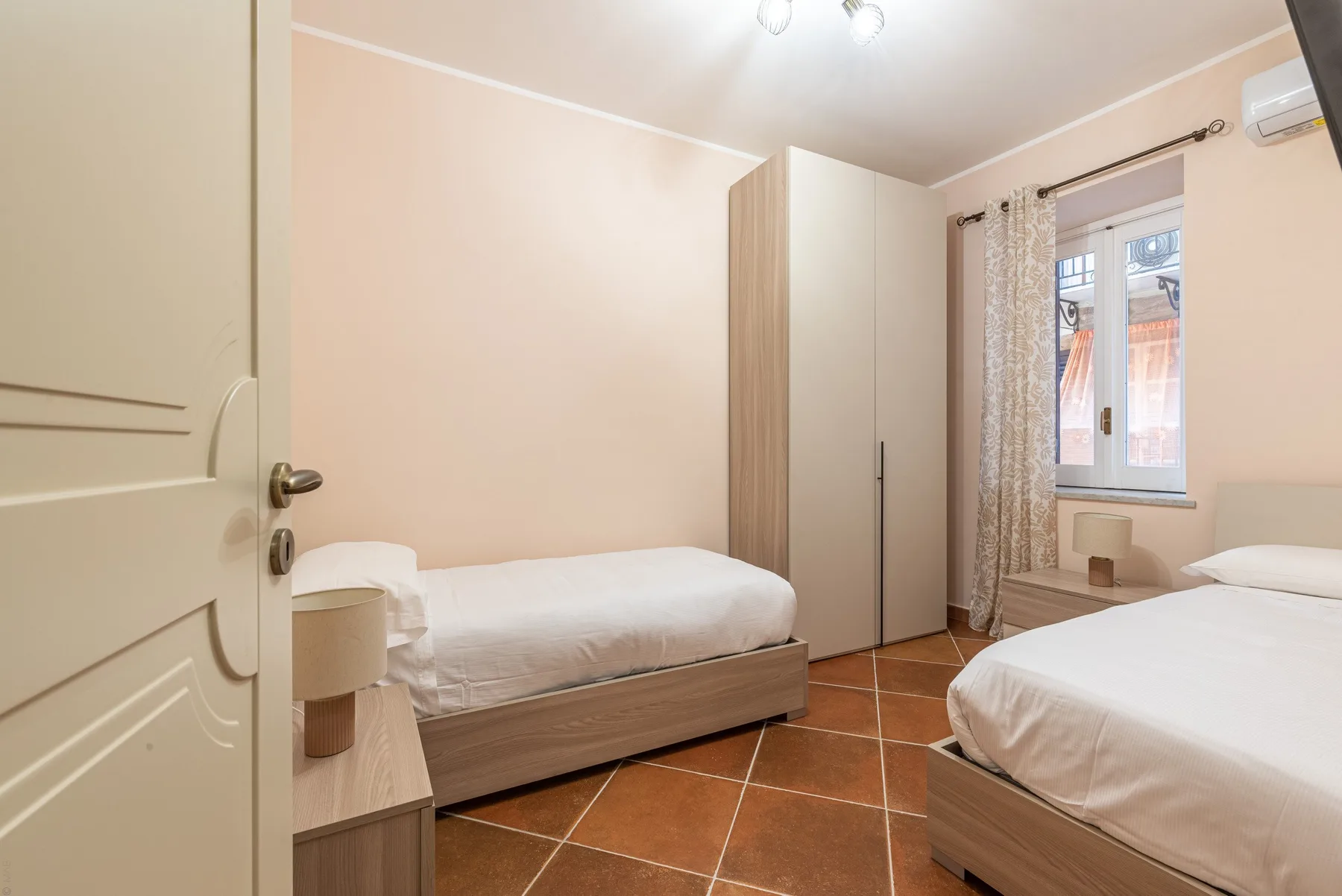 Un dormitorio con dos camas, un armario y una ventana.
