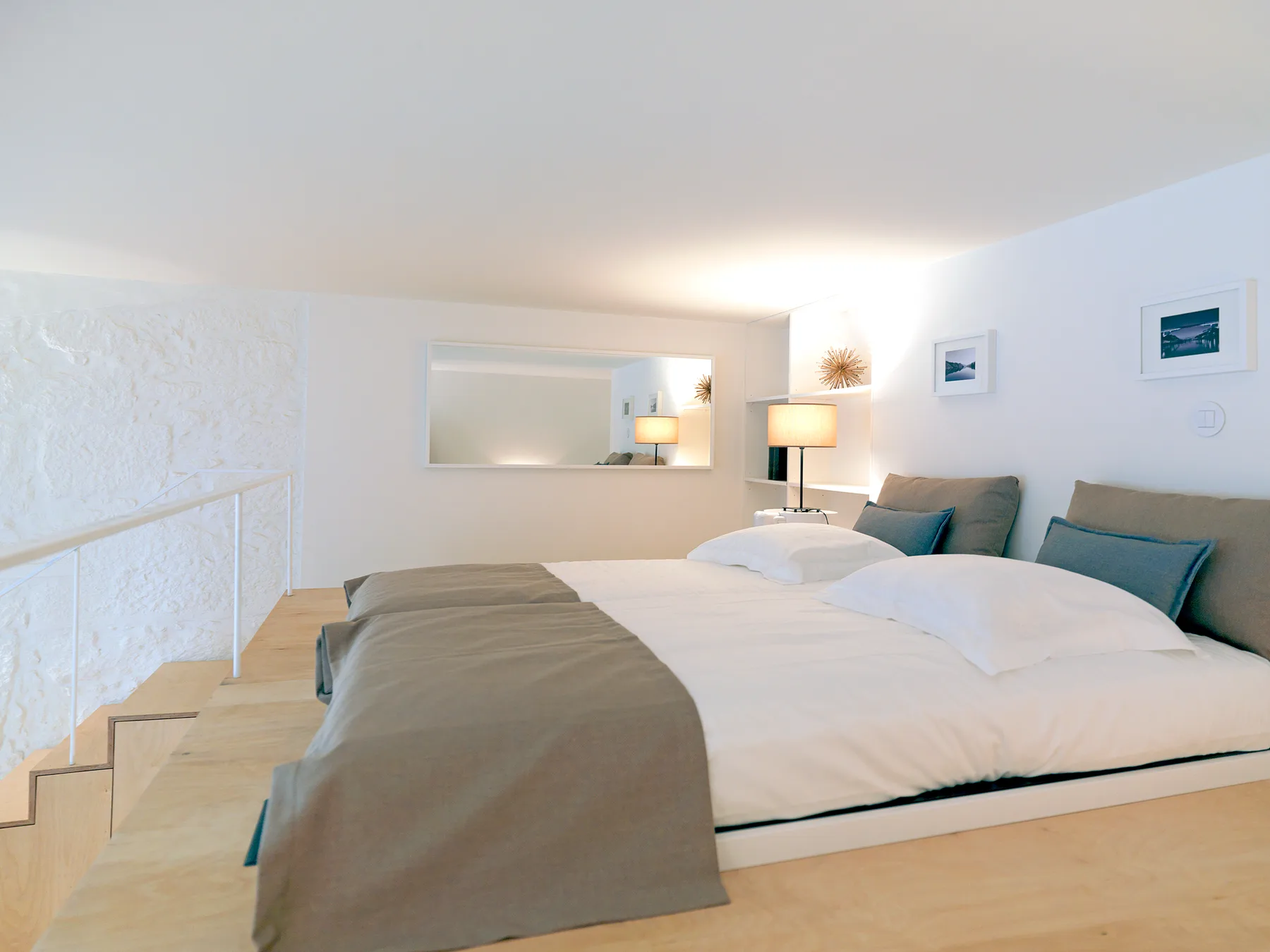 A bright bedroom with a large bed and a wall mirror.