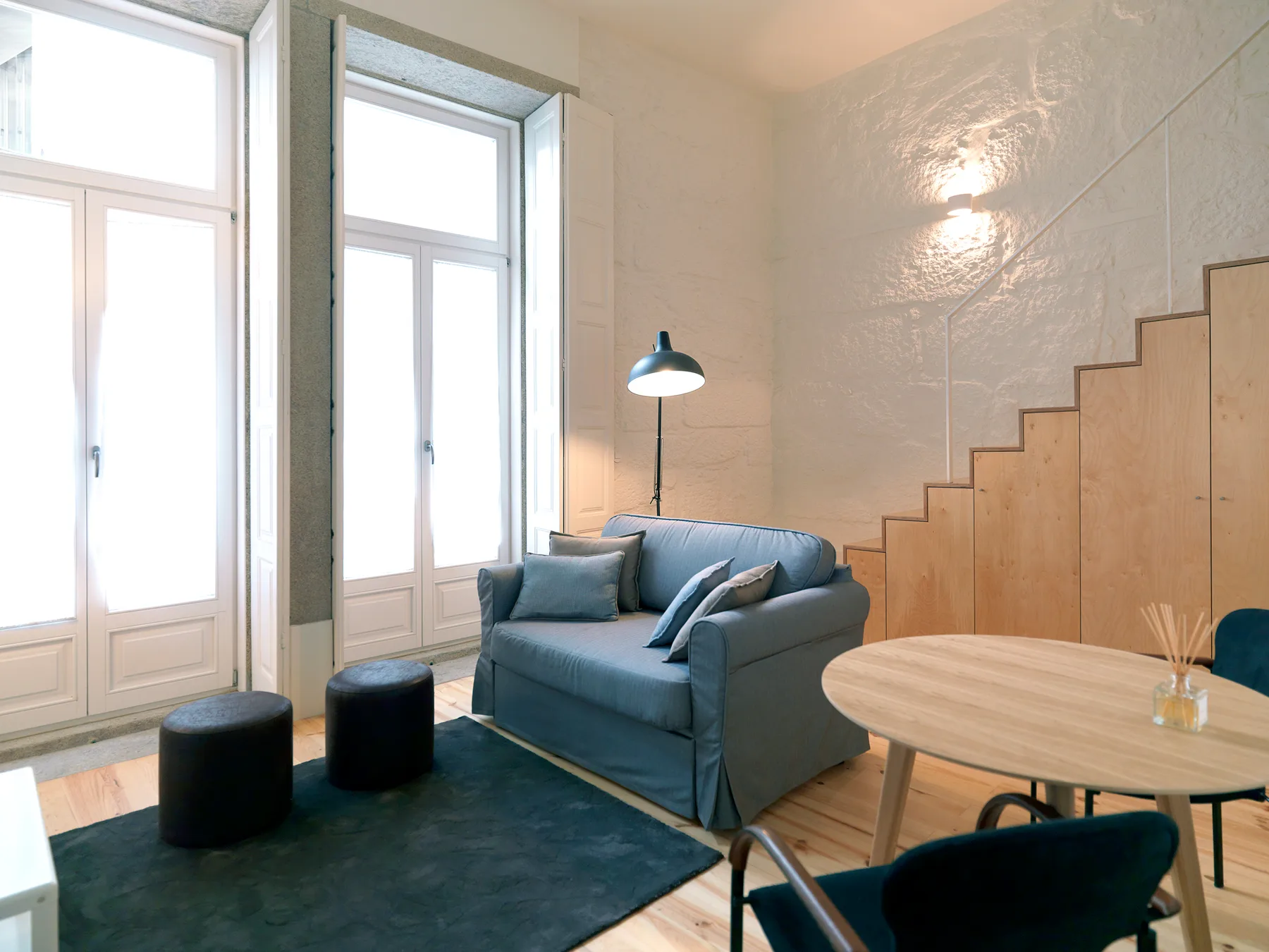 A living room with seating beside tall windows and a round table.