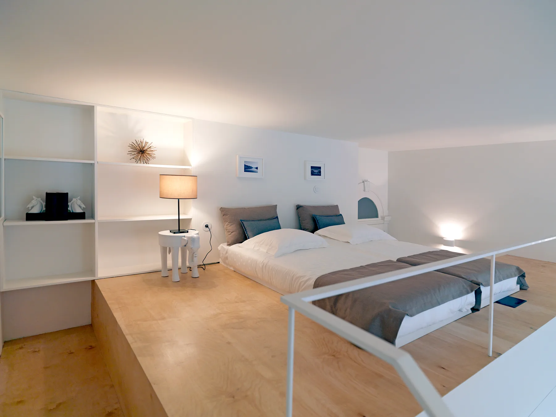 A bright bedroom with a bed, bedside lamp, and built-in shelving.