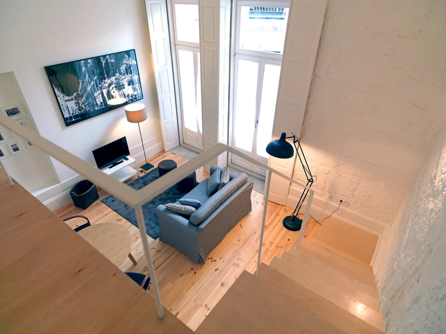 A bright living room with a sofa, television, and tall windows.