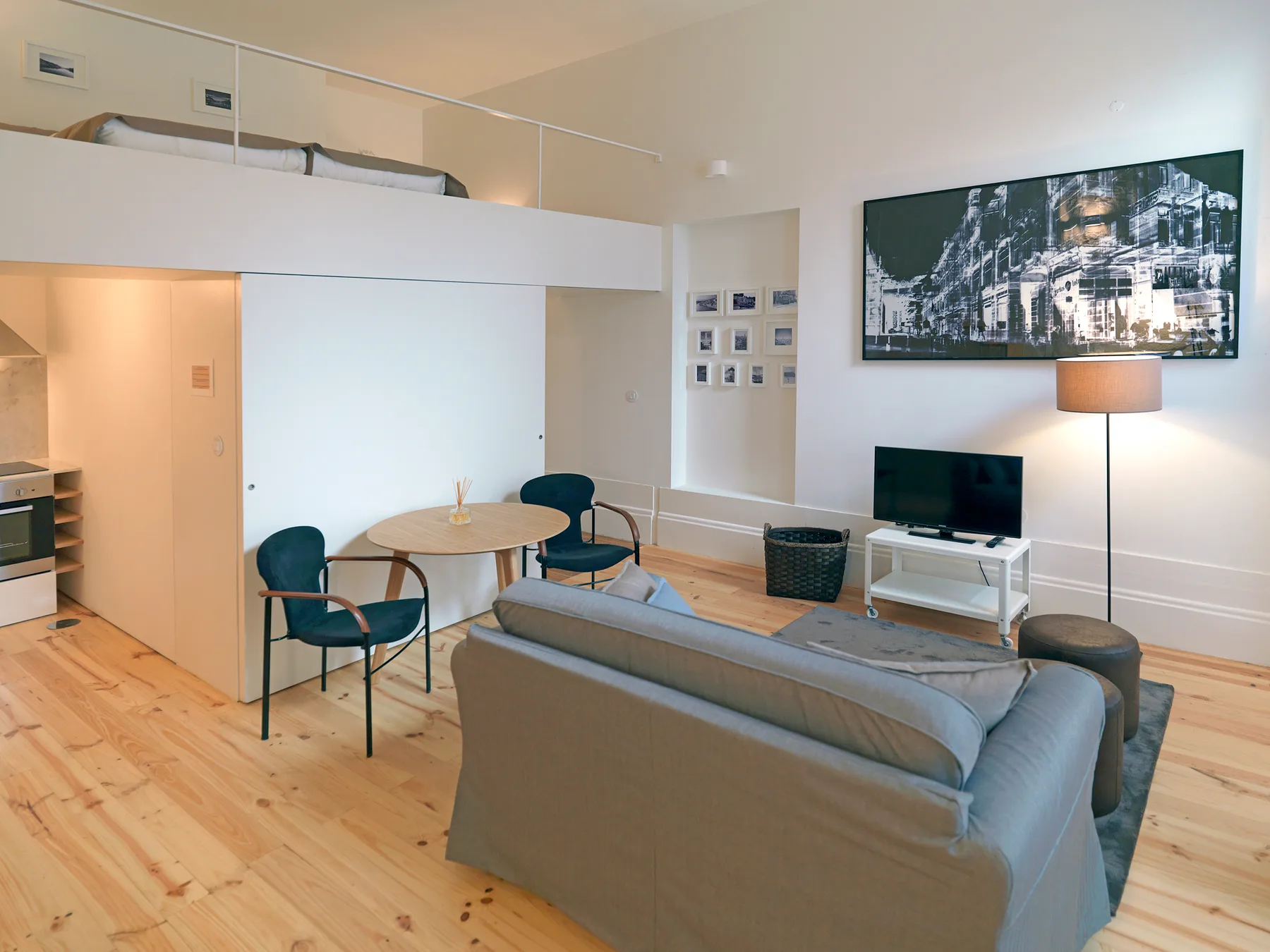 A modern living area with a dining table and seating beneath a loft bed.