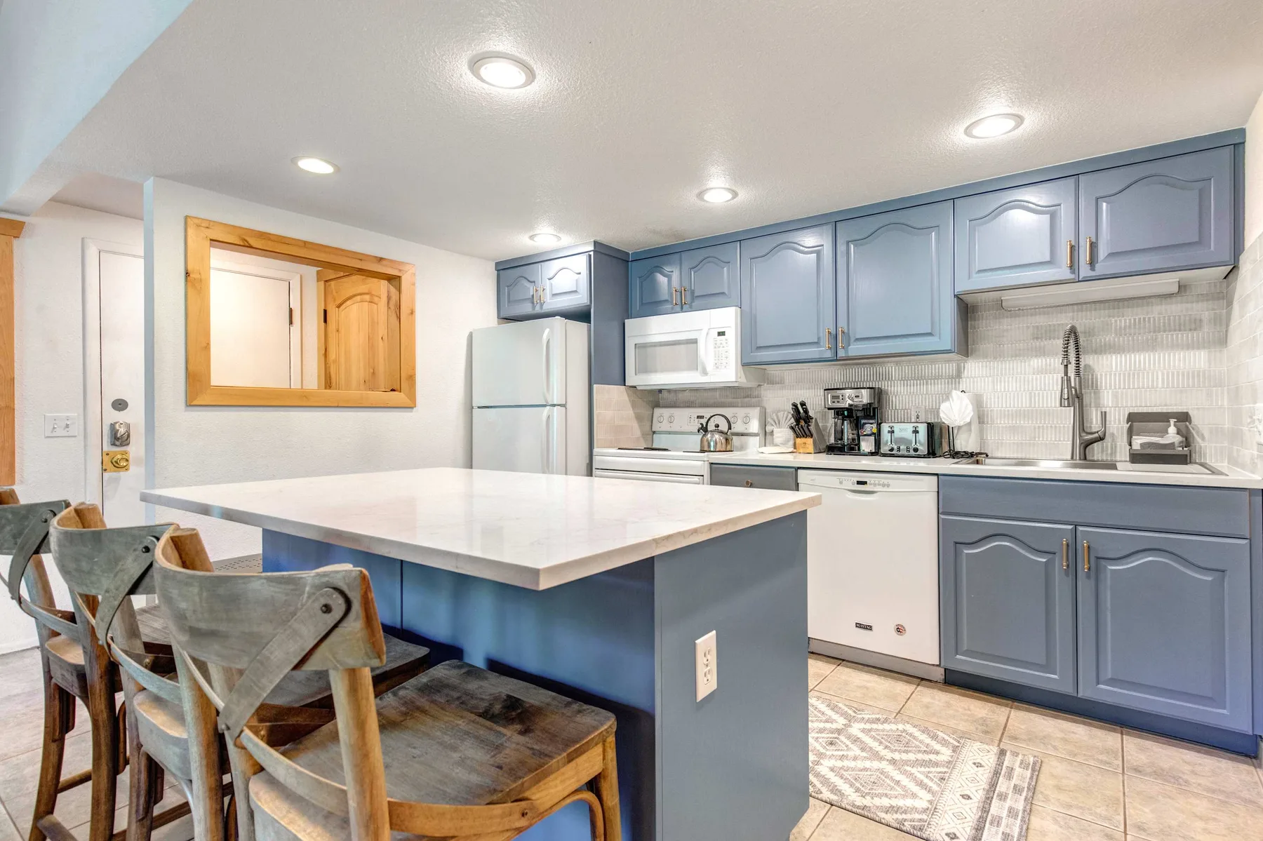 A kitchen with a large island and blue cabinetry.