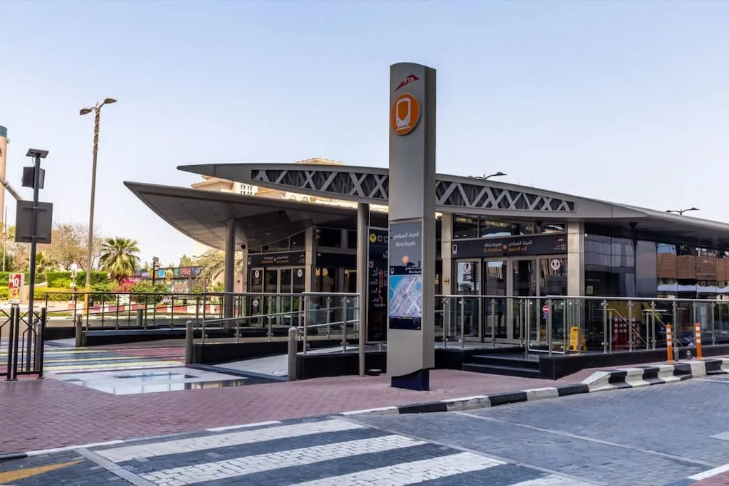 Una estación de transporte moderna con una plataforma cubierta y un letrero alto al frente.