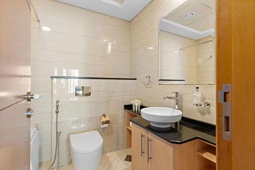 Un baño luminoso con mampara de ducha, inodoro y lavabo.