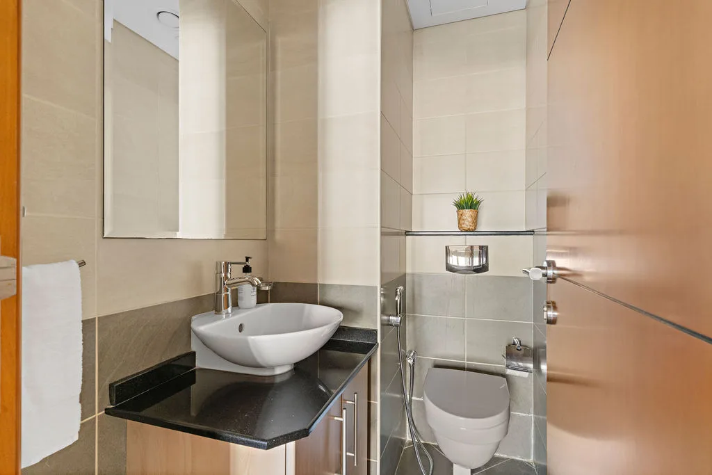 Un baño con lavabo, espejo e inodoro.