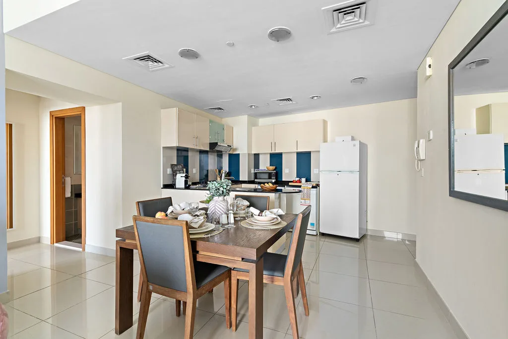 Un comedor con una mesa de madera y sillas frente a una cocina.