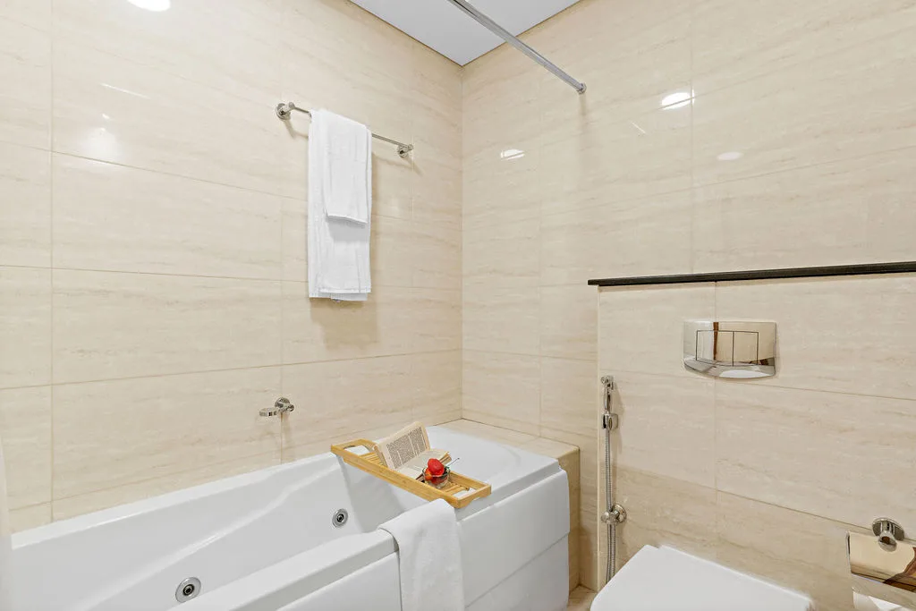 Un baño con azulejos, una bañera y una toalla colgada en la pared.