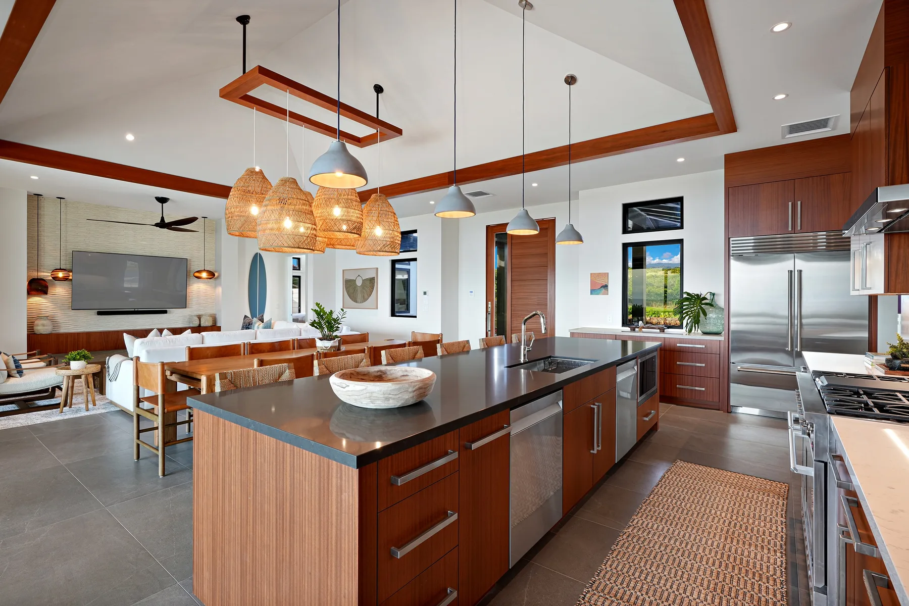 An open-plan kitchen and dining area with a large island and hanging lights.