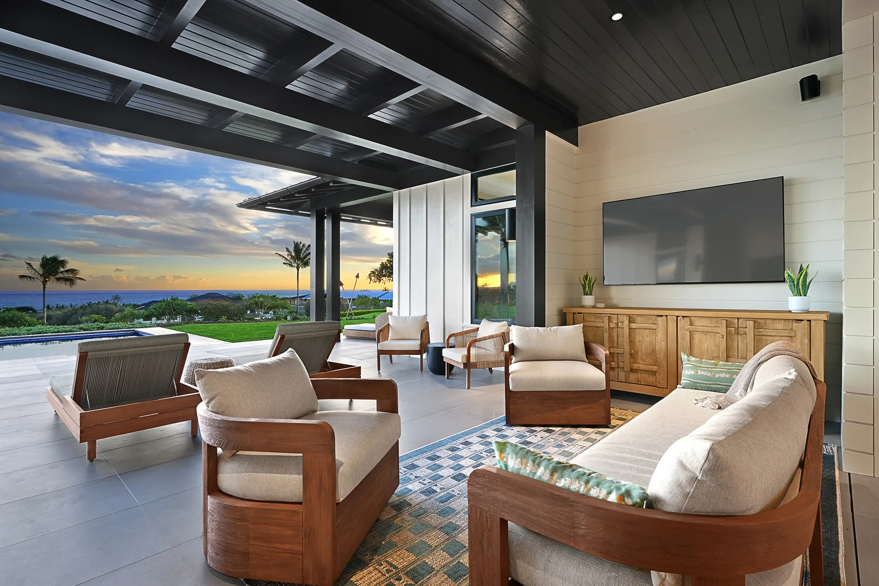 A covered outdoor lounge opens onto a garden and ocean view.