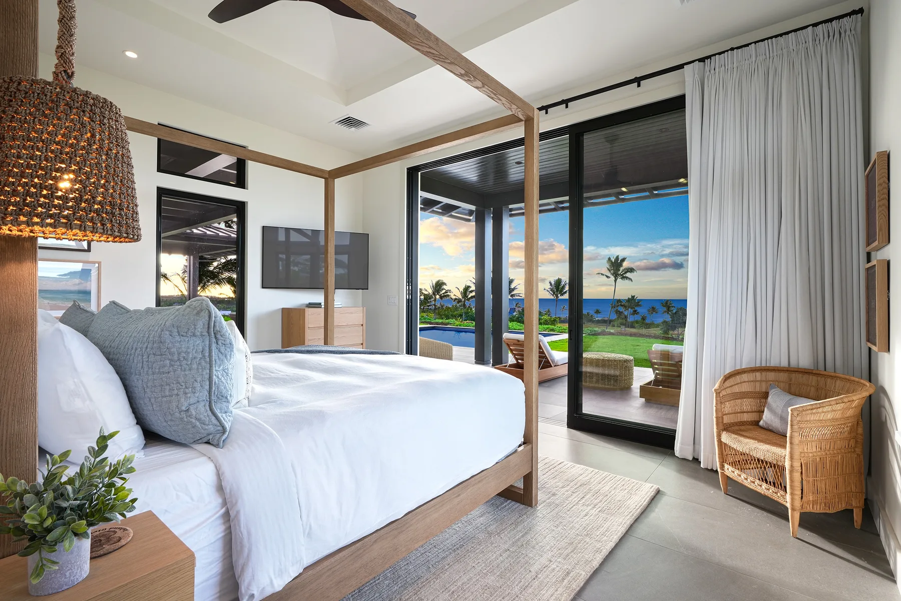 A bedroom with a large bed facing glass doors and a view of the sea.