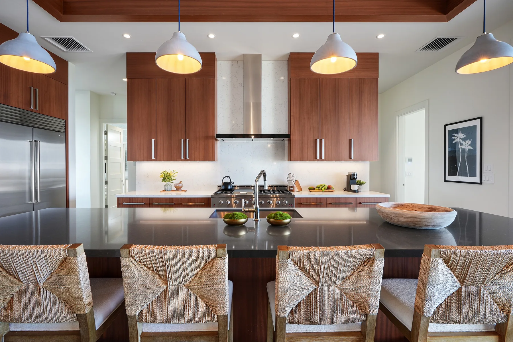 A modern kitchen features a central island with seating and pendant lights.