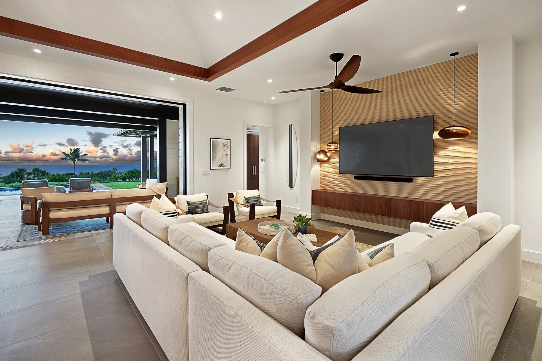 A bright living room with a large sectional facing a wall-mounted television.