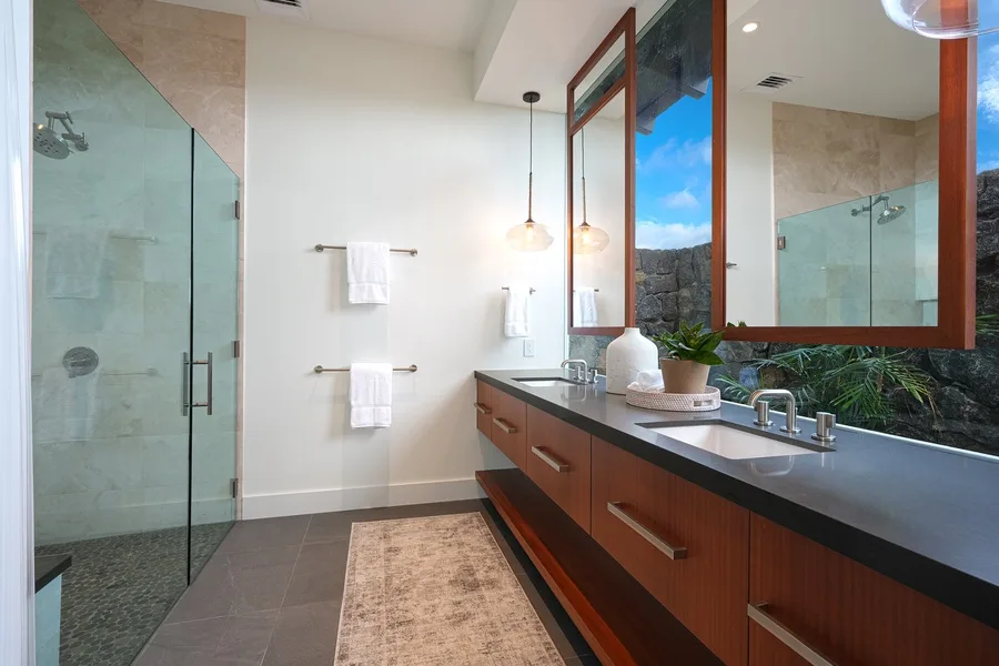 A modern bathroom with a glass shower and a long vanity beneath a large mirror.