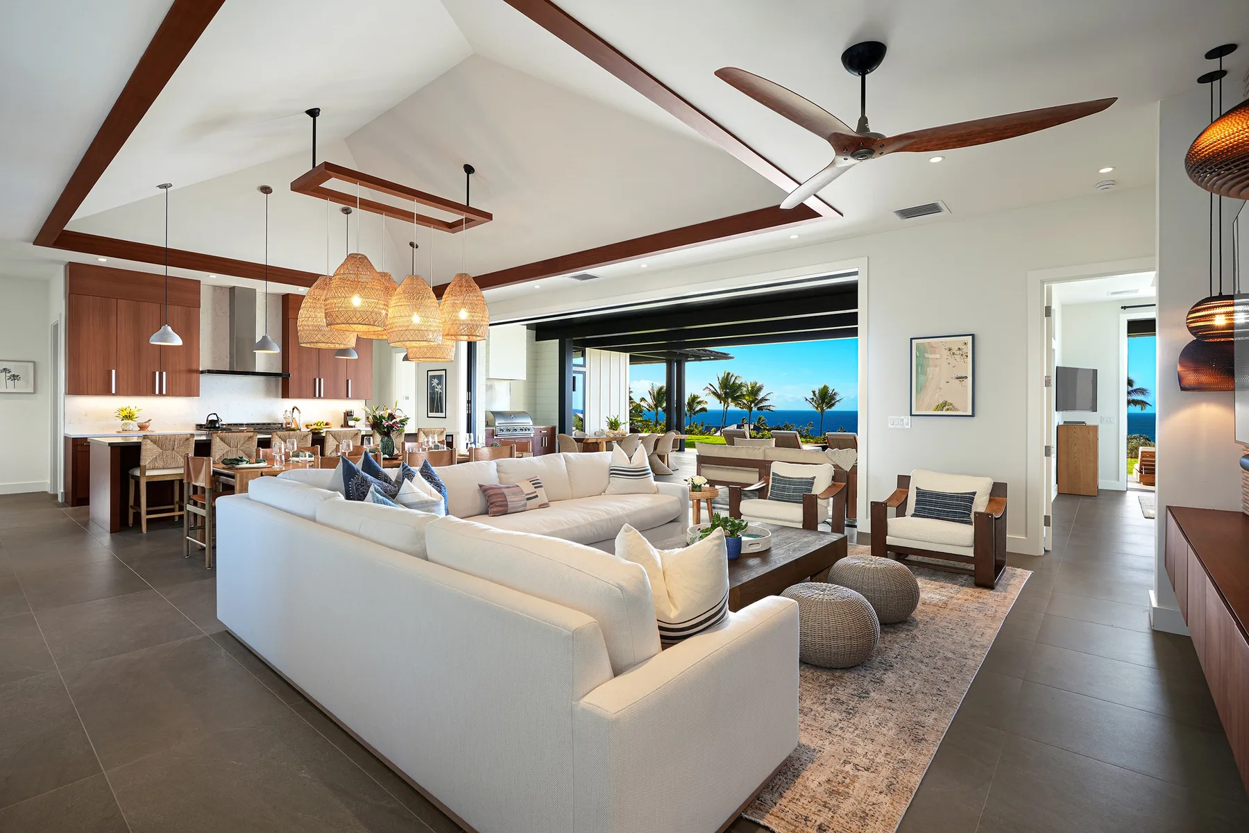 An open-plan living and dining area with seating beside a wide ocean-view window.