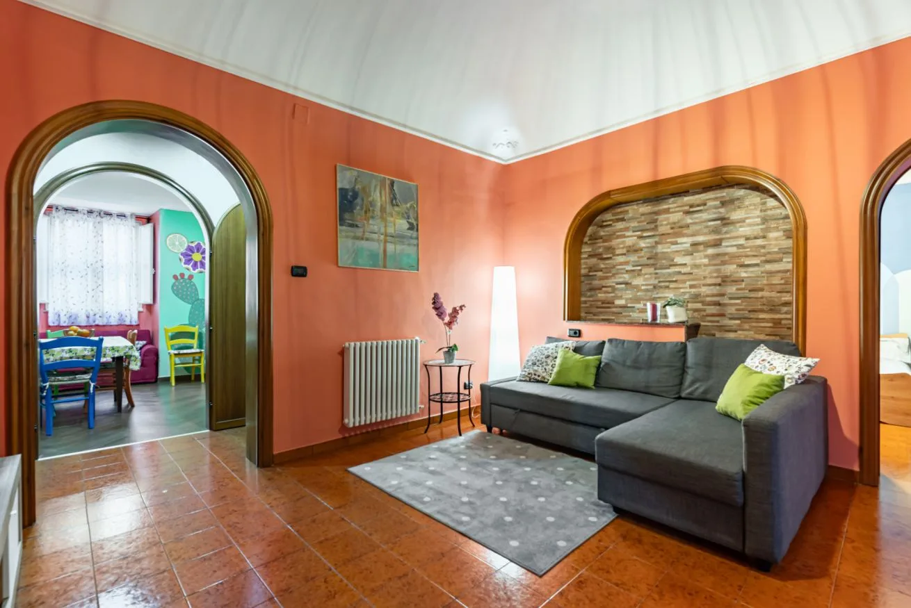 A living room with gray seating, a rug, and orange walls.