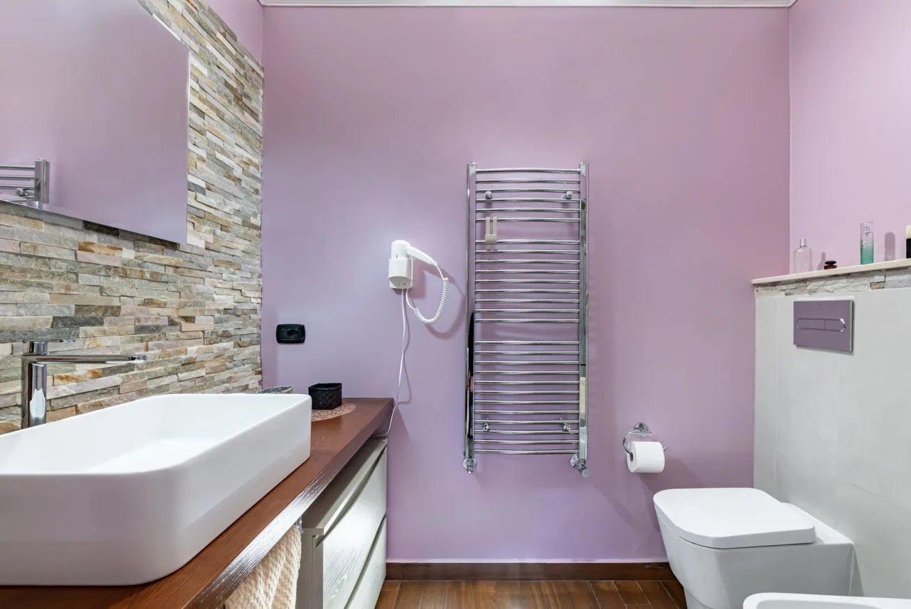 A bathroom with a bathtub, toilet, and wall-mounted towel warmer.
